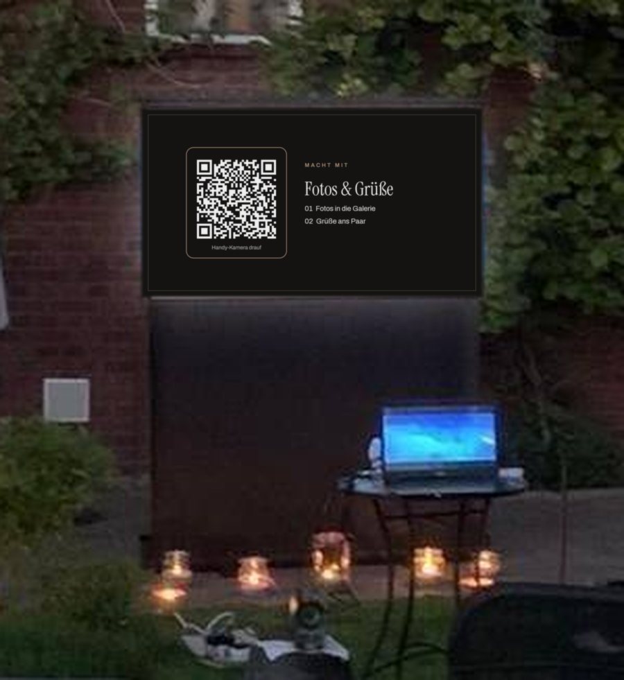 Fernseher im Garten mit der Folie „Macht mit“ und QR-Code, davor Windlichter