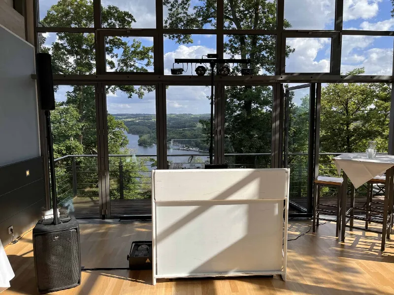 Weißes DJ-Pult, Lautsprecher und Lichtstativ vor der Glasfront mit Blick auf den See im Jagdhaus Schellenberg