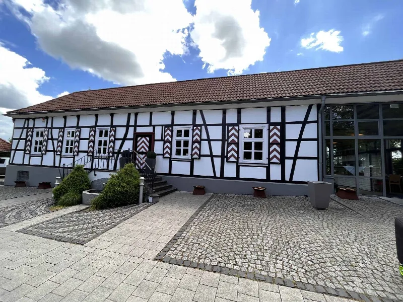 Weiß-schwarzes Fachwerkhaus mit rot-weißen Fensterläden und gepflastertem Hof des Jagdhaus Schellenberg