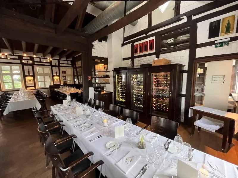 Tafel mit Kerzen und Gläsern, dahinter ein Weinklimaschrank mit Flaschen und ein Durchgang zur Küche