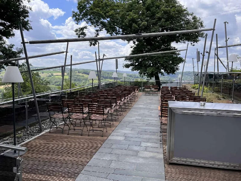 Stuhlreihen auf der Holzterrasse des Jagdhaus Schellenberg mit Steinweg in der Mitte und Weitblick ins Tal