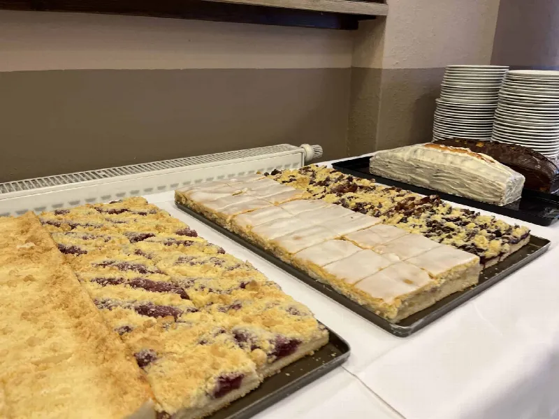 Kuchenbuffet mit Streuselkuchen, Zuckerguss-Blechkuchen und Kastenkuchen auf weißer Tischdecke